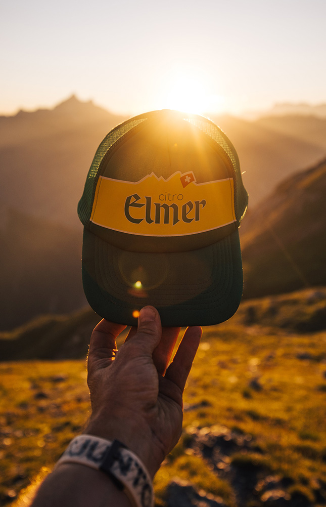 Kappe mit Logo im Sonnenuntergang gehalten