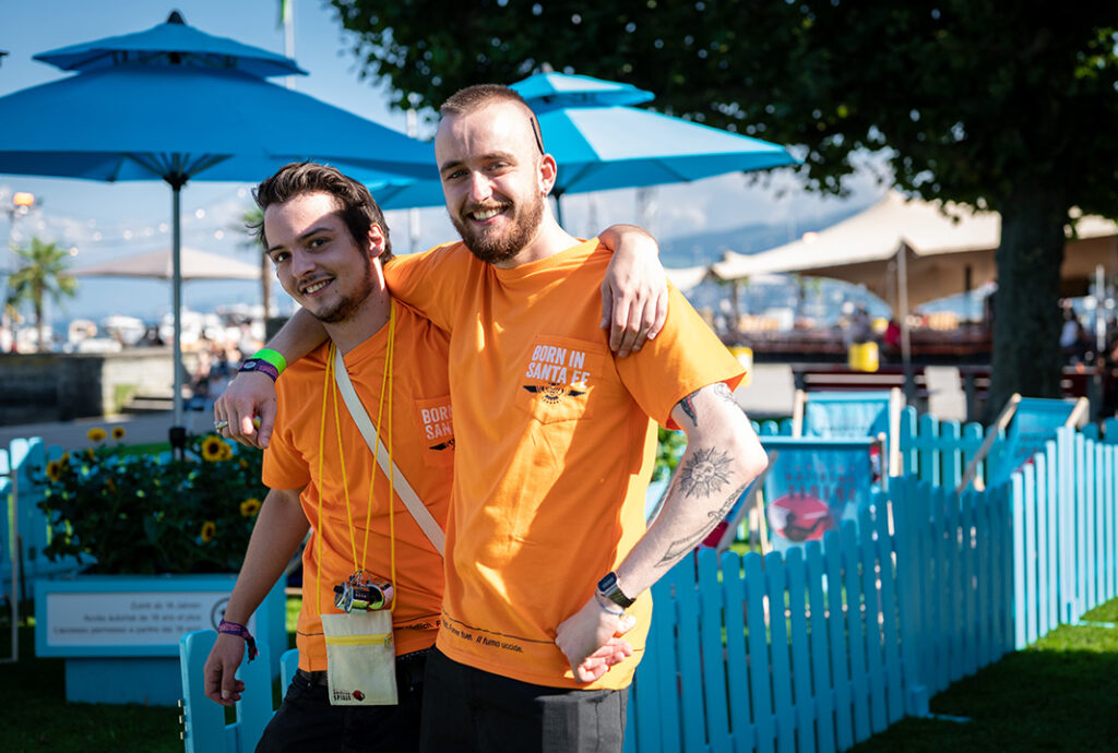 Zwei lächelnde Männer in orangenen Shirts umarmen sich