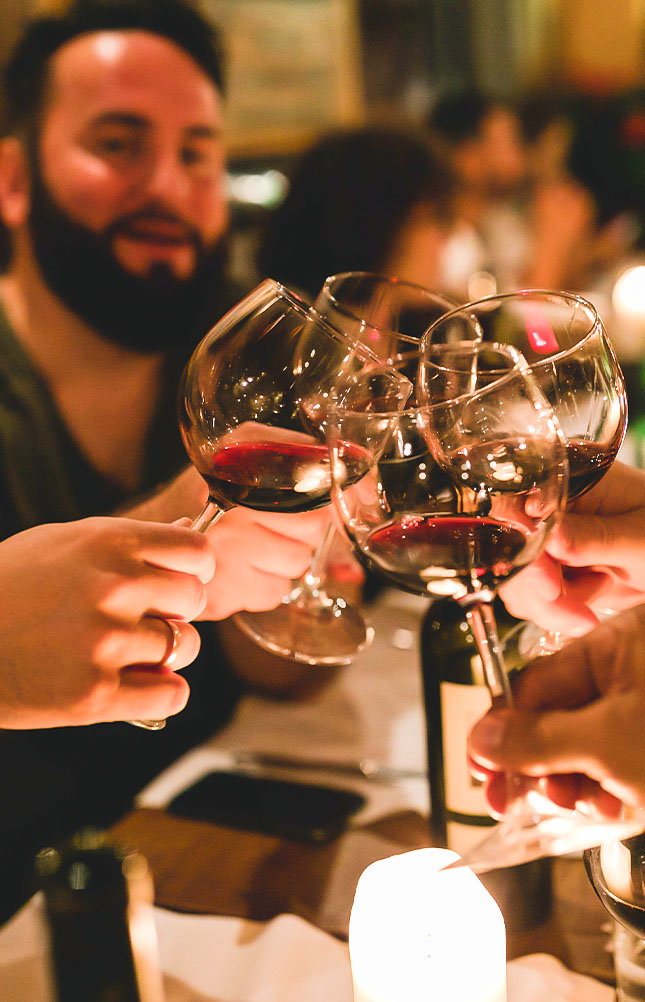 Freunde prostet mit Rotwein an Kerzenlicht