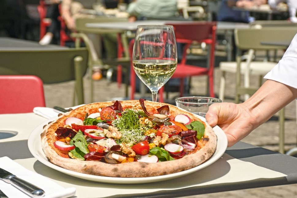 Pizza mit Gemüse und Weinglas im Freien
