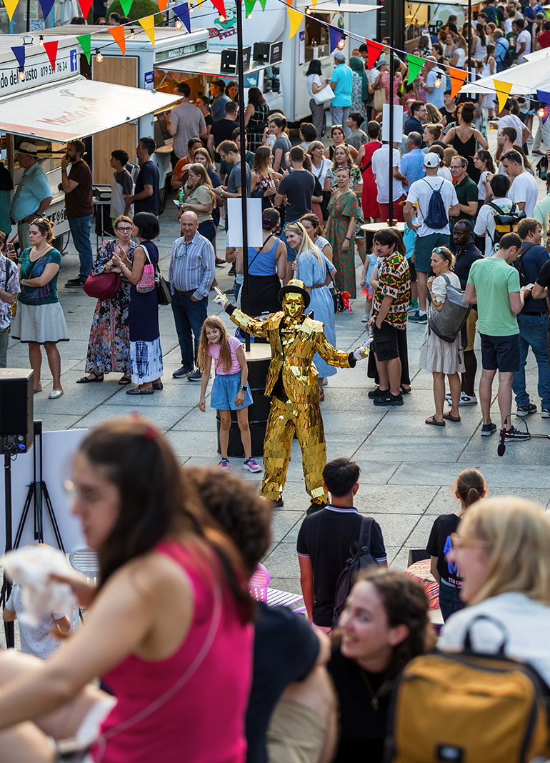 Goldene Statue unter Menschenmenge auf Straßenfest