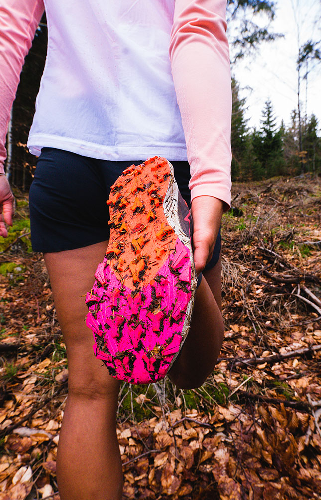 Läufer zeigt schlammige, rosa Schuhe im Wald