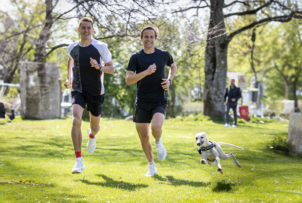 Zwei Männer und Hund laufen im Park