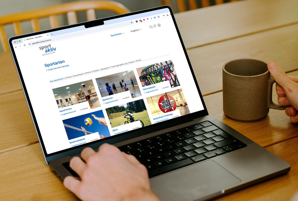 Laptop zeigt Sport-Webseite auf Holztisch