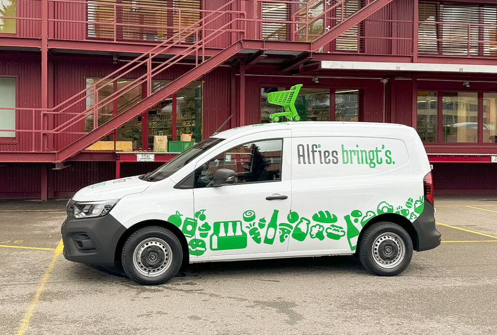 Lieferwagen mit grüner Lebensmittelwerbung vor Lagerhaus