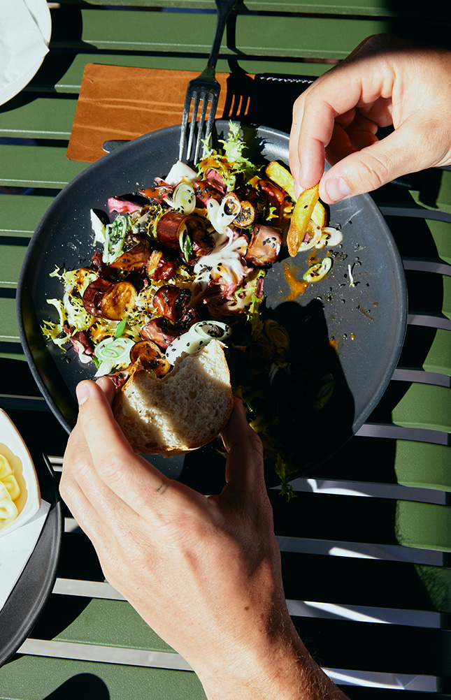 Person isst gemischten Salat im Sonnenlicht