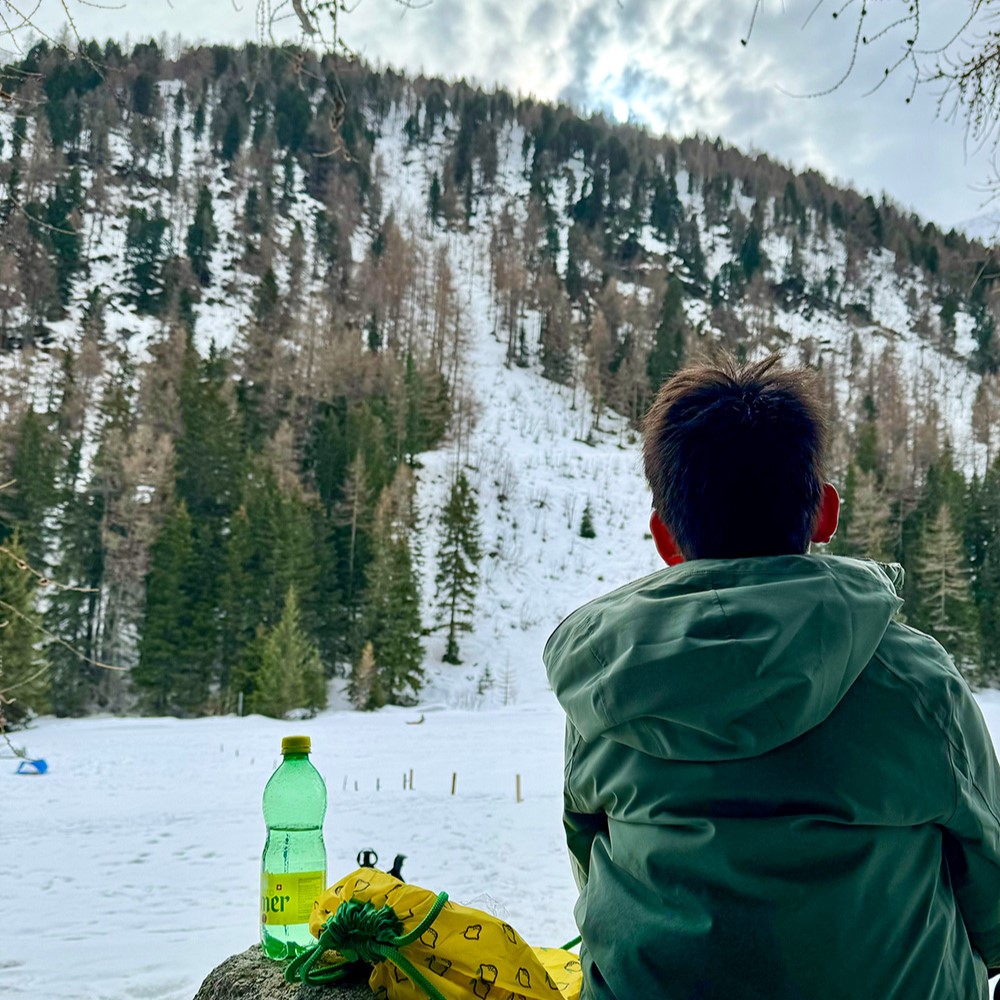 Mann blickt auf verschneiten Bergwald