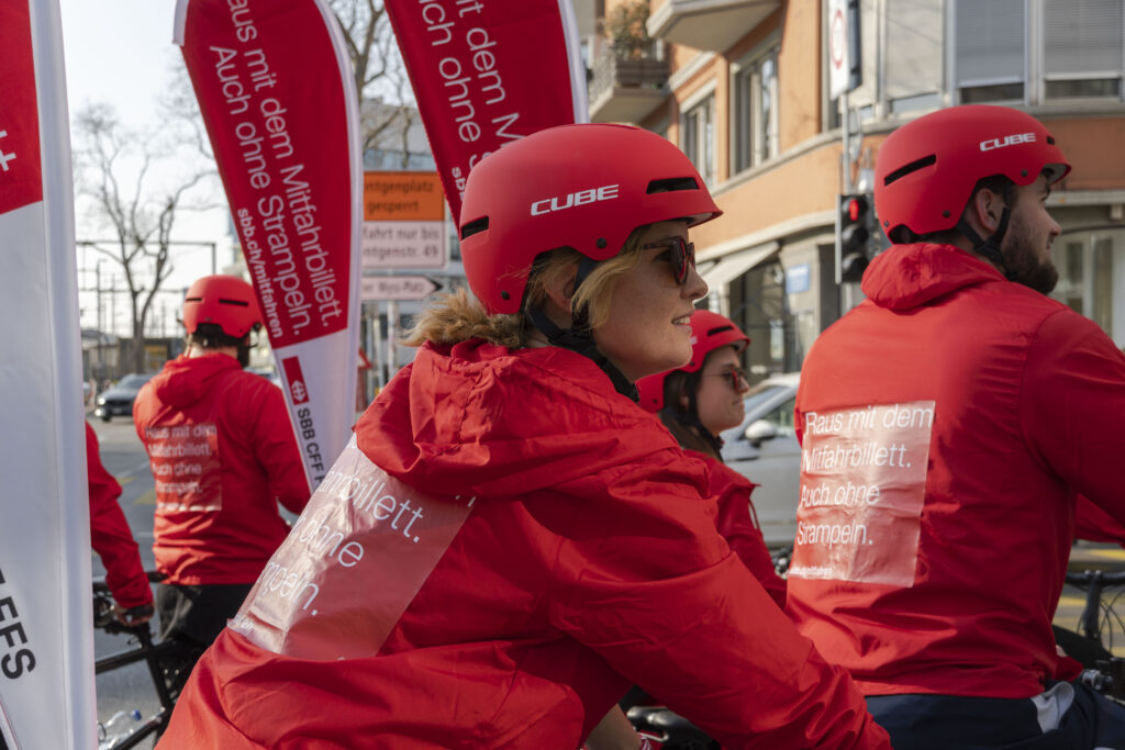 Personen in roten Jacken und Helmen auf Fahrrädern
