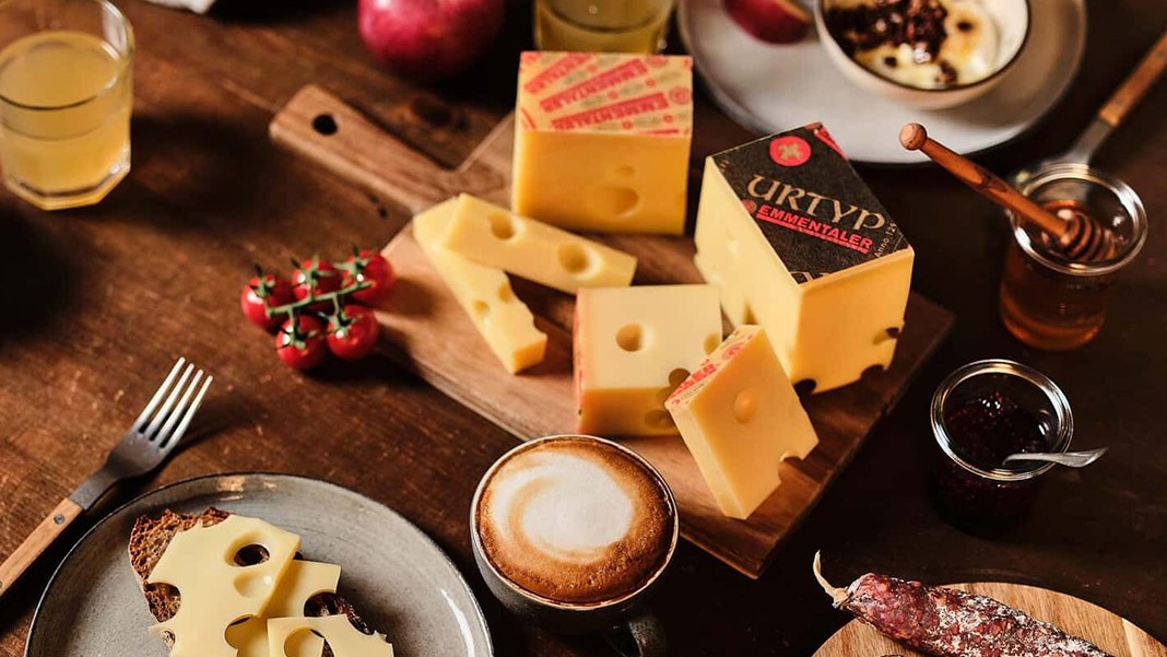 Käseplatte mit Kaffee und Beilagen auf Holztisch