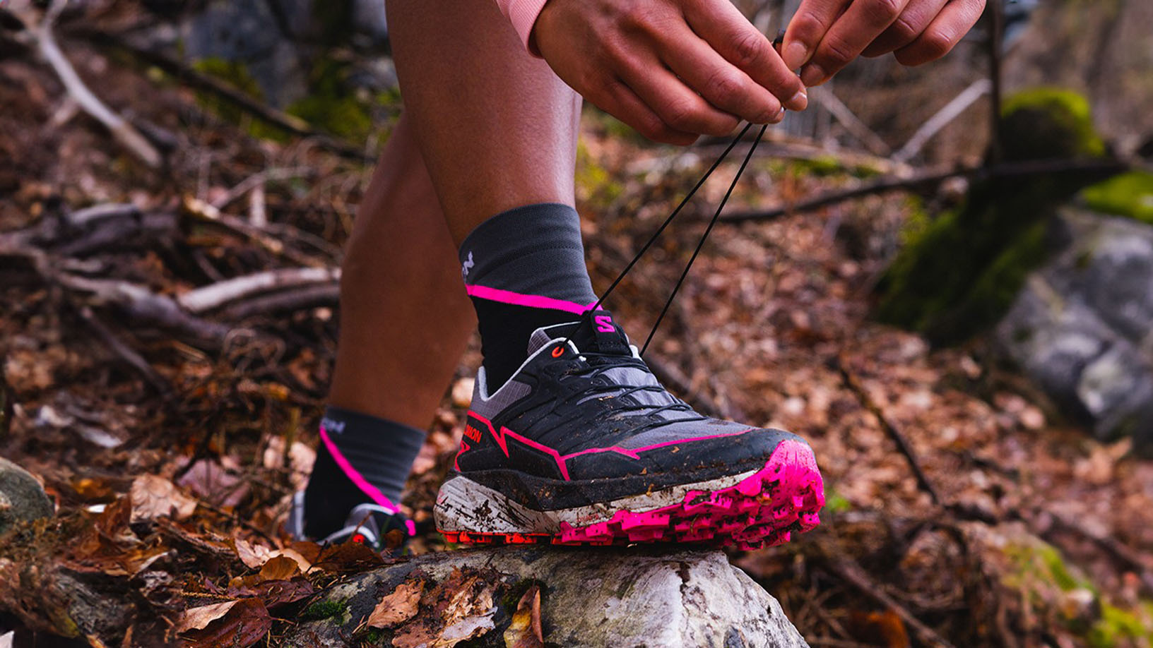 Person bindet Wanderschuhe im Wald